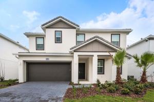 a white house with a garage at 10Br Retreat With Private Pool & Spa in Kissimmee
