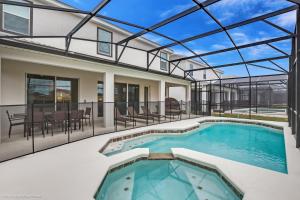 a house with a swimming pool with a glass roof at 10Br Retreat With Private Pool & Spa in Kissimmee