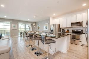 a kitchen with white cabinets and a bar with stools at 10Br Retreat With Private Pool & Spa in Kissimmee