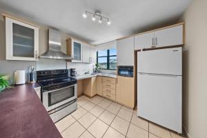 a kitchen with white cabinets and a refrigerator at Beachfront Aquatika Resort- Style-Pools & Ocean in Rio Grande