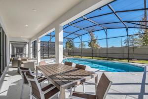 a patio with a table and chairs and a swimming pool at Ev2613 - Grand Horizon Manor in Kissimmee