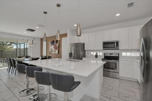 a kitchen with a large white island with bar chairs at Ev2613 - Grand Horizon Manor in Kissimmee