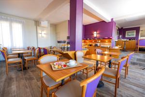 a restaurant with wooden tables and chairs and purple walls at Hotel Aguado in Dieppe