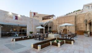 a patio with tables and chairs and umbrellas at Petra Guest House Hotel in Petra