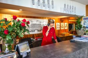 a woman talking on a cell phone in a restaurant at Hotel Aguado in Dieppe