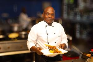 a chef holding a plate of food in a kitchen at Visiwa Beach Resort in Watamu +63 photos
