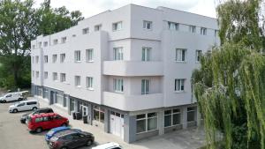a white building with cars parked in a parking lot at Apartmány Škodova Přerov in Přerov