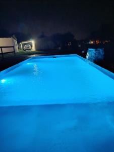 a swimming pool lit up with blue lights at night at Cabañas EL VALLE in Villa Rumipal +3 photos