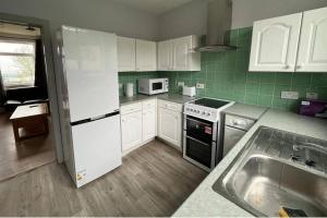 a kitchen with white appliances and green tiles at 3 Bed House Sleeps 5 - Free Parking - Tv & WiFi in Sheffield