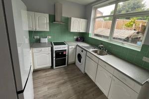 a kitchen with white cabinets and a sink and a window at 3 Bed House Sleeps 5 - Free Parking - Tv & WiFi in Sheffield +11 photos