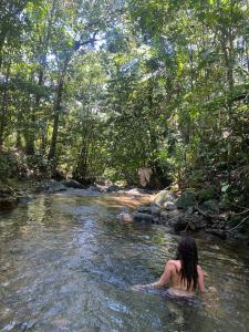a woman sitting in the water in a river at Reserva Wanaka, San Carlos in Cocorná