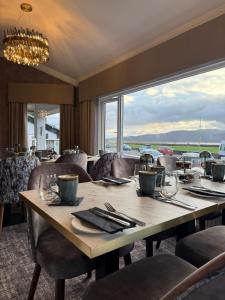 a dining room with a table with chairs and a large window at The Lilly Restaurant With Rooms in Llandudno