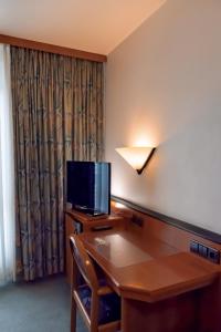 a hotel room with a desk with a television on it at Hotel Brößler in Stockstadt am Main