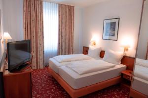 a hotel room with a bed and a flat screen tv at Hotel Brößler in Stockstadt am Main +29 photos
