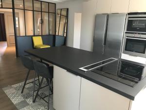 a kitchen with a black counter and a refrigerator at Studio Girofle dans Maison d'hôtes L'écrin des Saveurs in Schwenheim