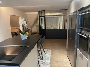 a kitchen with a black counter top and a refrigerator at Studio Girofle dans Maison d'hôtes L'écrin des Saveurs in Schwenheim