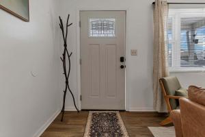 a white door in a living room with a plant at Housepitality - The Southside Ranch in Columbus +23 photos