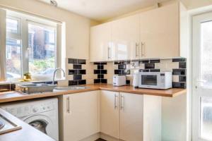 a kitchen with white cabinets and a microwave at House Sleeps 5 - WiFi & Tv in Luton