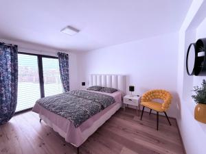 a bedroom with a bed and a chair and a window at Villa Vita - GLORIA in Slovenj Gradec