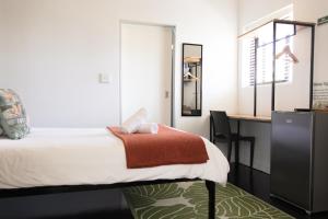 a bedroom with a desk and a bed with a red blanket at Foools Inn - Trendy Rooms available in the Heart of Sea Point! in Cape Town