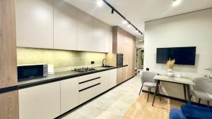 a kitchen with white cabinets and a table and a tv at MOLODIST 16 Irpin in Irpin +8 photos