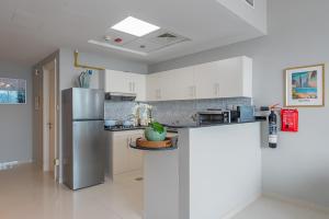 a kitchen with a stainless steel refrigerator and white cabinets at Urban Chic - Marina Bay in Abu Dhabi