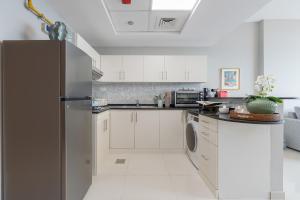 a kitchen with white cabinets and a stainless steel refrigerator at Urban Chic - Marina Bay in Abu Dhabi