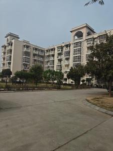 an empty parking lot in front of a large apartment building at Shivaya Homes in Chhatikara