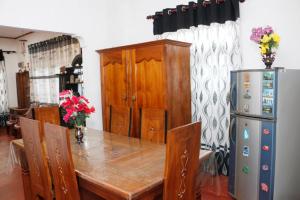 a dining room with a table and a refrigerator at Ivy Cottage- Midigama in Midigama East