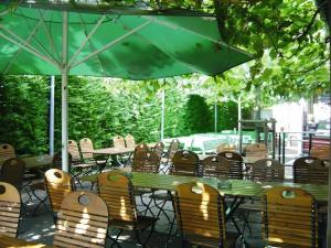 a table with chairs and a green umbrella at Hotel Brößler in Stockstadt am Main