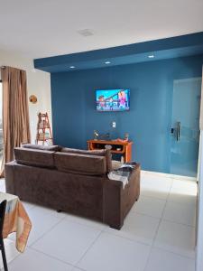 a living room with a brown couch and a blue wall at Comfort right on the sand! in Paracuru