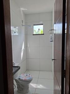 a white bathroom with a toilet and a shower at Comfort right on the sand! in Paracuru