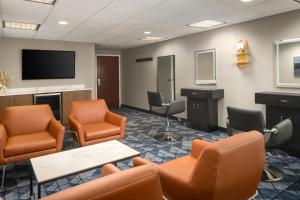 a waiting room with chairs and a flat screen tv at Courtyard Hartford Cromwell in Cromwell