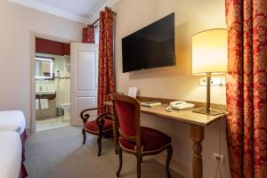 a hotel room with a desk and a bedroom at Cit'Hotel Sphinx - Hotel in Montélimar
