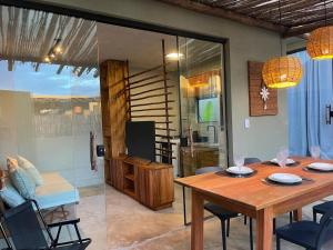a dining room with a table and a living room at Bangalôs Riviera do Patacho in Pôrto de Pedras