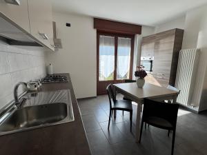 a kitchen with a sink and a table with chairs at La Gare Apartments - Zerbion in Châtillon