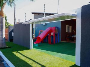 a house with a slide in a yard at Suítes privativas, camas confortáveis, piscina, churrasqueira e playground, Roupa de Cama e tolha de banho. in Rubinéia