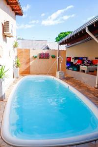 a large blue swimming pool on a patio at Suítes privativas, camas confortáveis, piscina, churrasqueira e playground, Roupa de Cama e tolha de banho. in Rubinéia