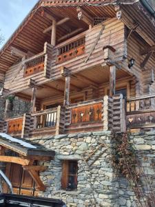 a large wooden building with a deck on top at le chalet in Planay