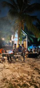 a group of people sitting at a table under a palm tree at Sekinchan Tiny House - Moslim Only in Sekinchan