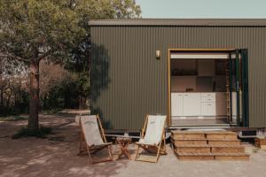 two chairs sitting in front of a green building at HolaCamp la Franca in Las Conchas