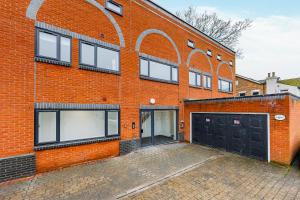 an orange brick building with two garages and two garage doors at Studio Room, Parking, Contractors and Relocators, Weekly Deals in Maidstone