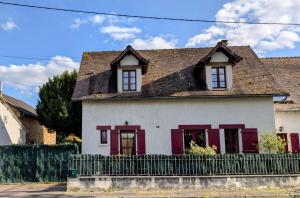 a white house with red windows and a fence at Les tuilières in Masléon