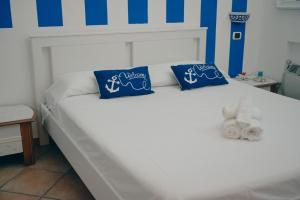 a white bed with blue and white pillows on it at Milion's House Apartments in Minori
