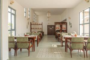 a dining room with tables and chairs and windows at Vanthra Vilas, Jawai - Luxury Villas with Private Pools in Bijāpur