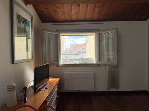 a room with a desk with a television and a window at Casa Petrucci centro storico, accesso ztl e park gratuito in Forlì