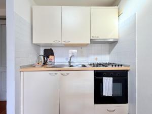 a kitchen with white cabinets and a black oven at Casa Petrucci centro storico, accesso ztl e park gratuito in Forlì