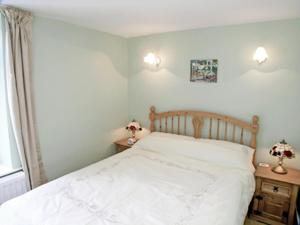 a bedroom with a white bed with two lamps on tables at Vale View Cottage in Cinderford