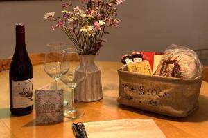 a table with a bottle of wine and a basket of flowers at Pets - Garden - Parking - Sleeps up to 4 - Hiking in Banchory