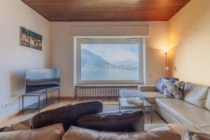 a living room with a couch and a large window at Villa La Perledina in Perledo